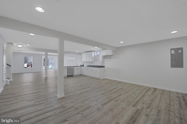 unfurnished living room featuring light wood-type flooring, electric panel, baseboards, and recessed lighting