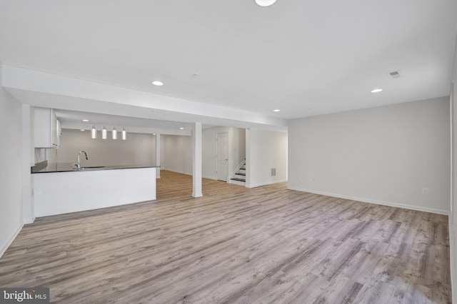 finished basement with visible vents, light wood-style flooring, and recessed lighting