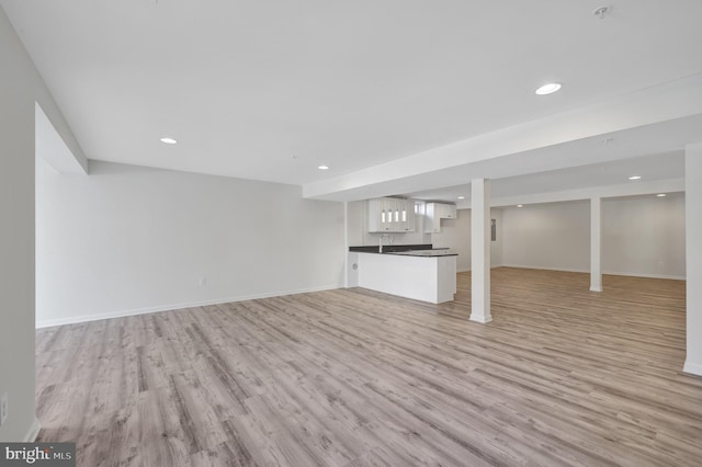 unfurnished living room with light wood-type flooring, baseboards, and recessed lighting