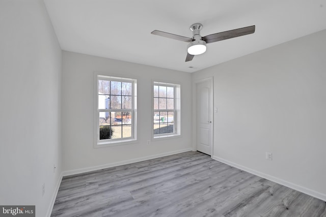 empty room featuring ceiling fan, light wood-style flooring, and baseboards