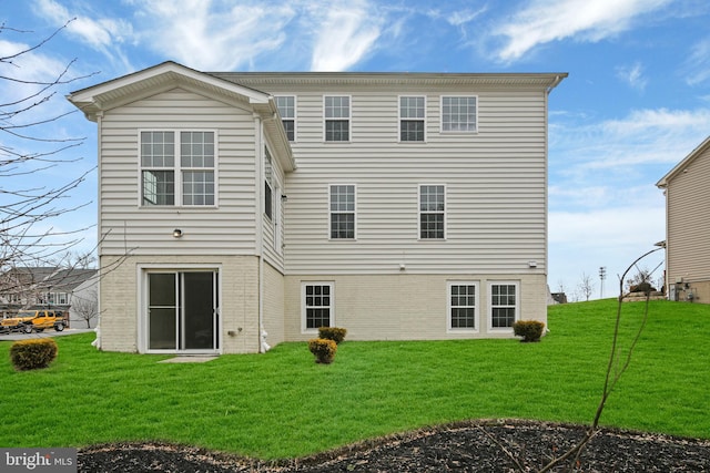 rear view of house with brick siding and a yard