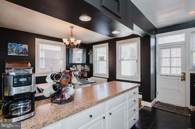 kitchen with pendant lighting, a notable chandelier, light countertops, white cabinets, and baseboards