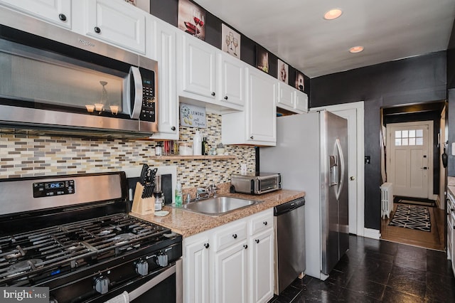 kitchen featuring stainless steel appliances, a sink, and white cabinetry