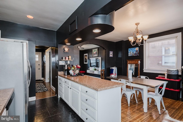 kitchen featuring dark wood finished floors, freestanding refrigerator, hanging light fixtures, a peninsula, and white cabinetry