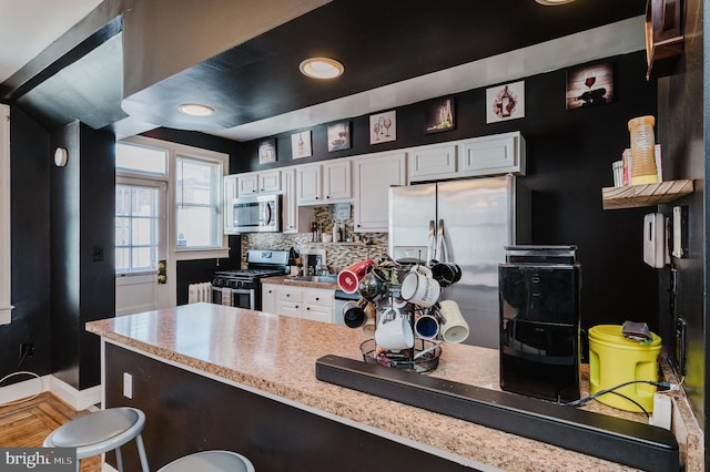 kitchen featuring stainless steel appliances, baseboards, white cabinets, light countertops, and tasteful backsplash