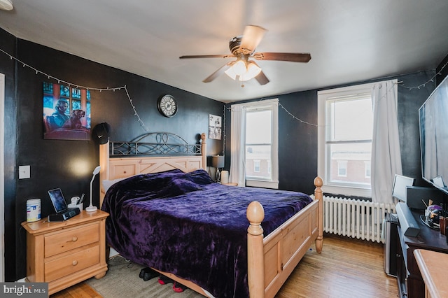 bedroom with light wood-style floors, a ceiling fan, and radiator