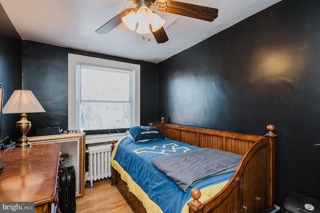 bedroom with a ceiling fan, light wood-style flooring, and radiator