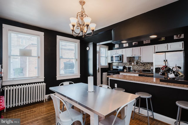 dining space with a chandelier, dark wood-style flooring, radiator heating unit, and a toaster