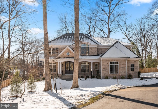 view of front facade featuring brick siding, fence, and french doors