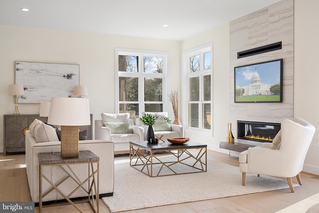living room featuring baseboards, a fireplace, wood finished floors, and recessed lighting