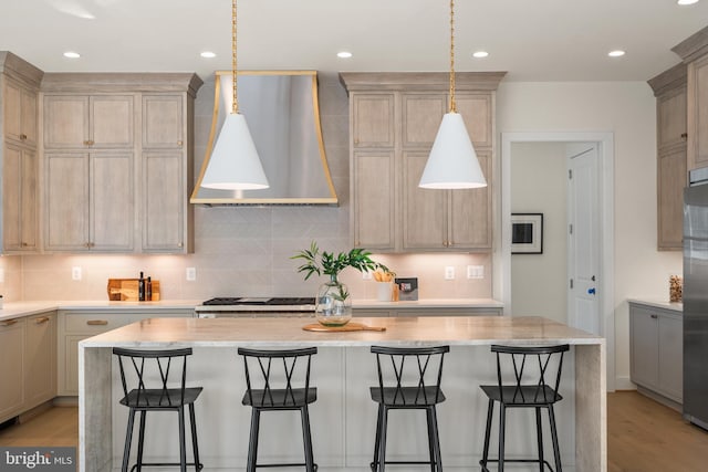 kitchen featuring a kitchen island, a breakfast bar, stainless steel fridge, and premium range hood