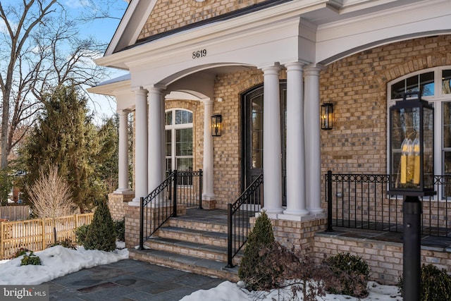 snow covered property entrance with a porch