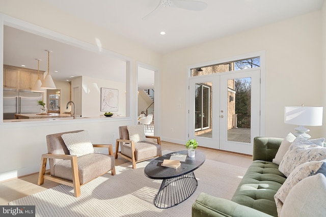 living area with a wealth of natural light, light wood-style floors, ceiling fan, and french doors