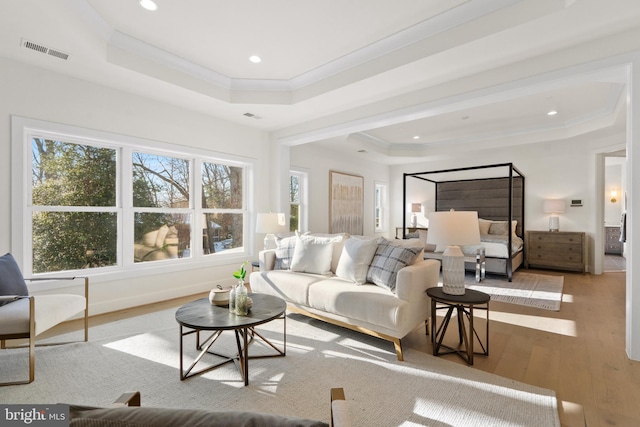 living room featuring visible vents, wood finished floors, crown molding, and a raised ceiling