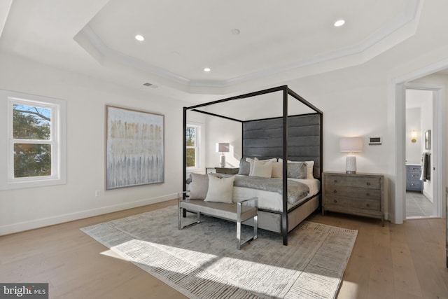 bedroom featuring visible vents, baseboards, ornamental molding, wood finished floors, and a tray ceiling