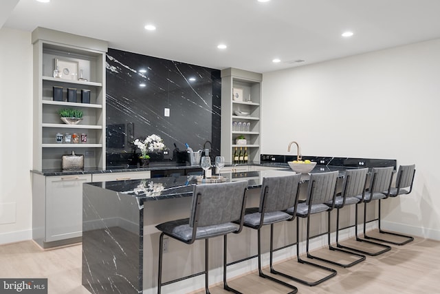 bar featuring decorative backsplash, baseboards, recessed lighting, built in features, and light wood-style floors