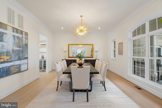 dining area featuring light wood-style flooring, a notable chandelier, crown molding, and visible vents