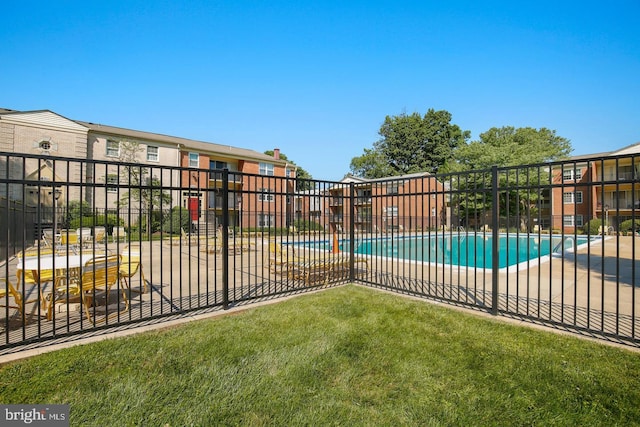 view of gate featuring fence, a community pool, and a lawn