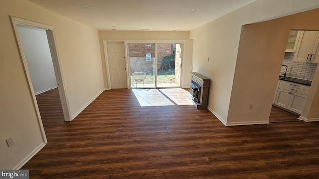 unfurnished living room with baseboards and dark wood-style floors