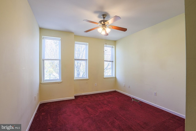 carpeted spare room featuring a wealth of natural light and ceiling fan