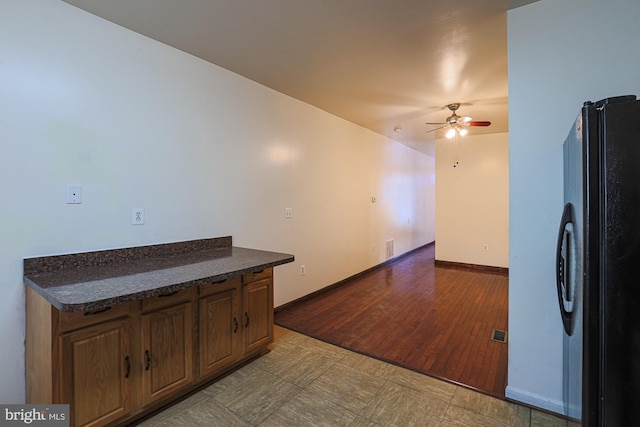 kitchen with black refrigerator, light hardwood / wood-style floors, and ceiling fan