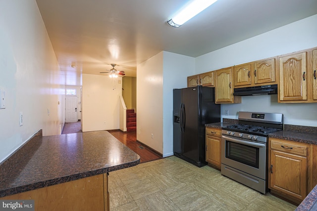 kitchen with stainless steel gas range oven, black refrigerator with ice dispenser, kitchen peninsula, and ceiling fan