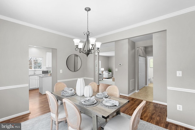 dining space featuring hardwood / wood-style floors, ornamental molding, and a chandelier