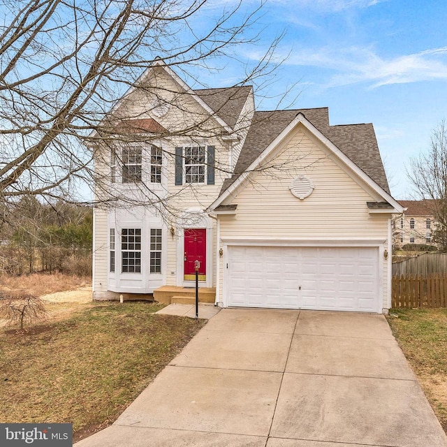 traditional home featuring a shingled roof, driveway, an attached garage, and fence