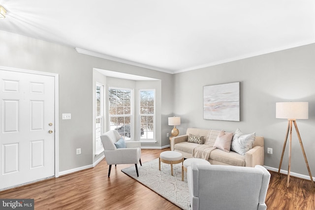 living room featuring crown molding, baseboards, and wood finished floors