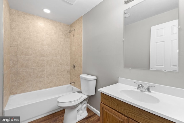 full bathroom with vanity, hardwood / wood-style floors, tiled shower / bath, and toilet