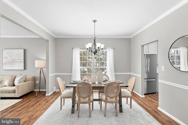 dining room featuring an inviting chandelier, crown molding, and light wood-type flooring