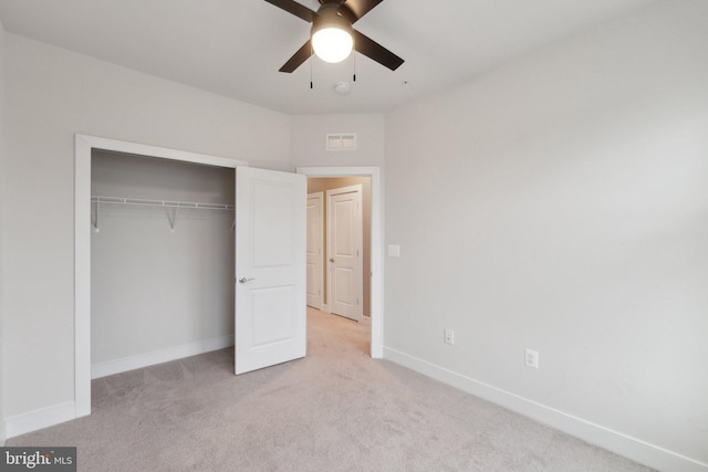 unfurnished bedroom featuring ceiling fan, light colored carpet, and a closet