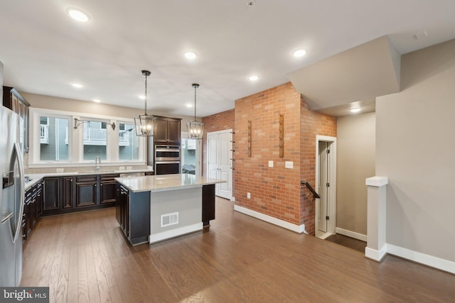 kitchen with dark brown cabinetry, hanging light fixtures, light stone countertops, and a center island