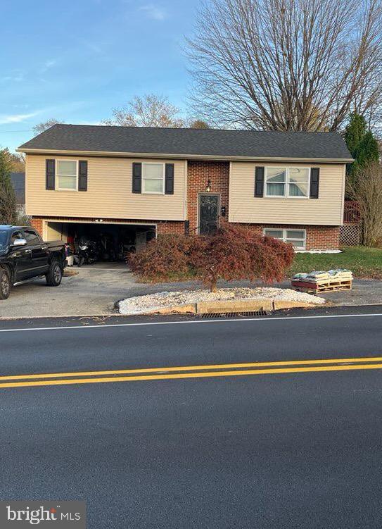 raised ranch featuring driveway and brick siding