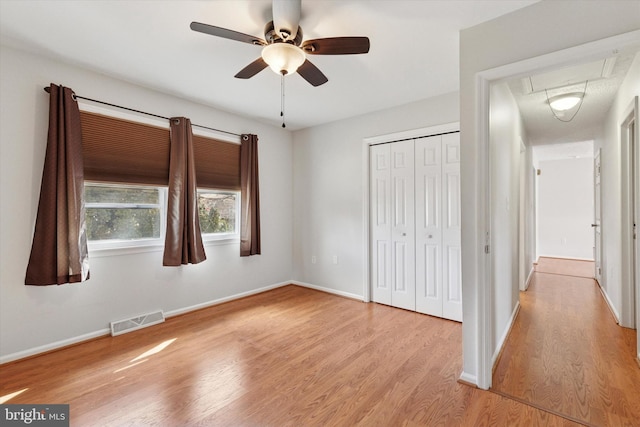 unfurnished bedroom with visible vents, baseboards, a closet, light wood-type flooring, and attic access