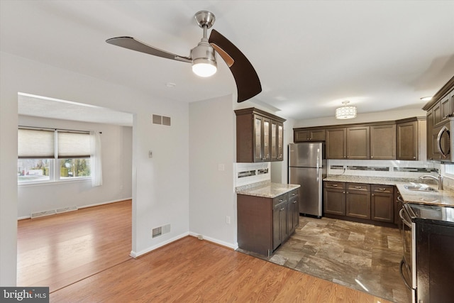 kitchen featuring tasteful backsplash, visible vents, light wood-style flooring, stainless steel appliances, and a sink