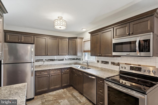 kitchen with a sink, appliances with stainless steel finishes, backsplash, and dark brown cabinets