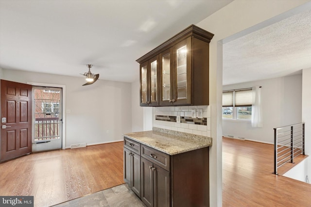 kitchen featuring a wealth of natural light, tasteful backsplash, dark brown cabinetry, and light wood-style floors