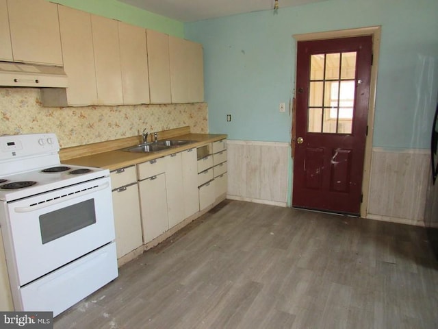 kitchen featuring range hood, sink, white electric range oven, cream cabinets, and light wood-type flooring