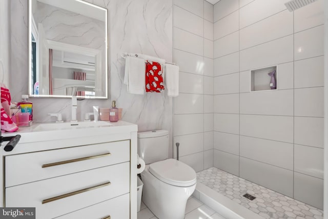 bathroom with vanity, tiled shower, and toilet