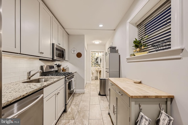 kitchen with appliances with stainless steel finishes, sink, wooden counters, and decorative backsplash