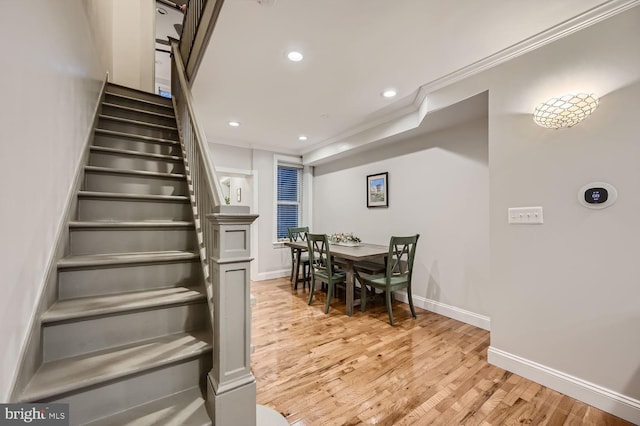 staircase with hardwood / wood-style floors and ornamental molding