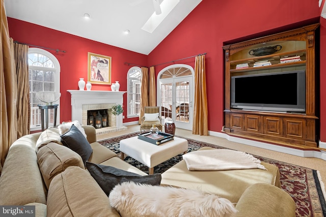 living room featuring a skylight, baseboards, a fireplace, and high vaulted ceiling