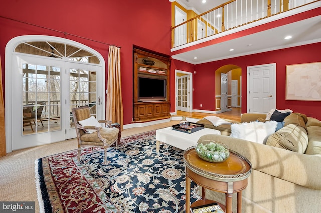 carpeted living area with arched walkways, a high ceiling, recessed lighting, and baseboards