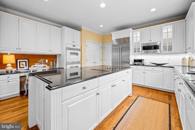 kitchen featuring dark countertops, white cabinets, and built in appliances