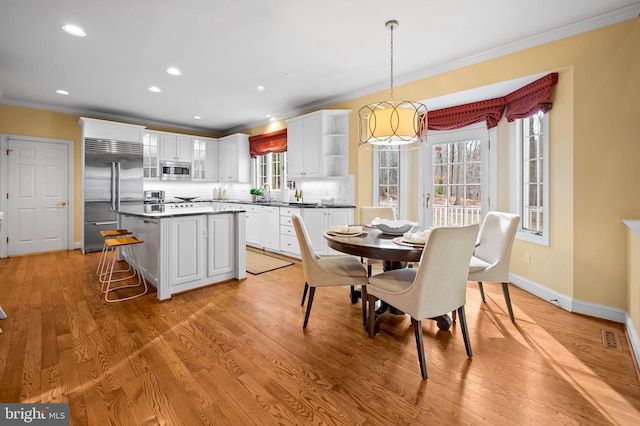 kitchen featuring built in appliances, light wood-style flooring, white cabinetry, ornamental molding, and tasteful backsplash