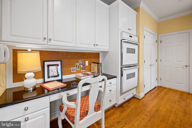 kitchen featuring double oven, light wood finished floors, dark countertops, and white cabinetry