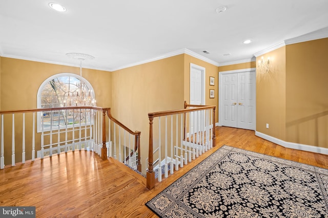 hallway with a chandelier, wood finished floors, an upstairs landing, baseboards, and crown molding