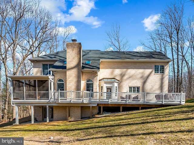 back of property featuring a yard, a chimney, a wooden deck, and a sunroom