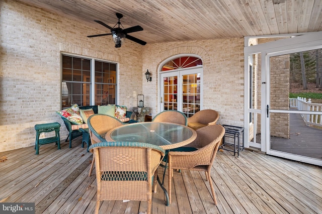 wooden deck with outdoor dining area, ceiling fan, and french doors